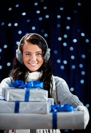 Pretty Caucasian girl in winter clothing on a blue background with glowing white lights.の写真素材