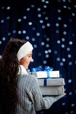 Pretty Caucasian girl in winter clothing on a blue background with glowing white lights.の写真素材