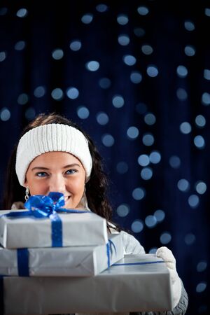 Pretty Caucasian girl in winter clothing on a blue background with glowing white lights.の写真素材