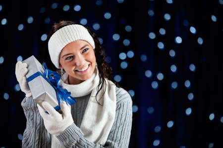 Pretty Caucasian girl in winter clothing on a blue background with glowing white lights.の写真素材