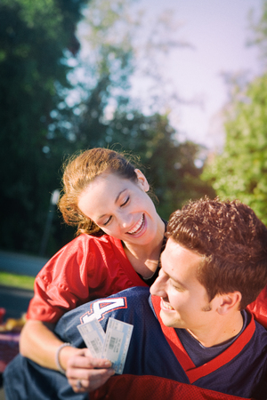 Tailgating: Woman Rides Piggyback While Holding Game Ticketsの写真素材