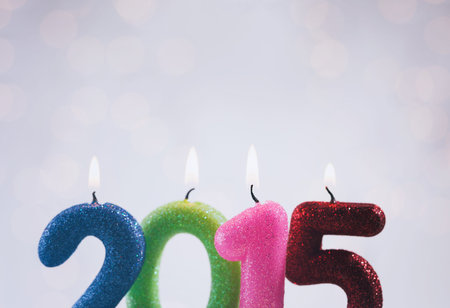 Lit candles for 2015 against a lit background.