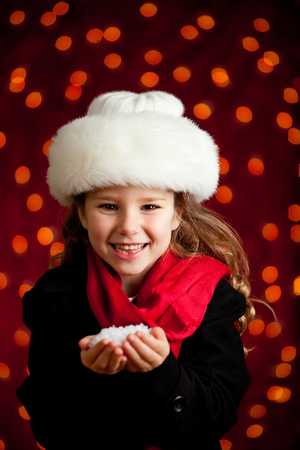 Beautiful holiday series with a cute girl on a glowing red background, dress in winter clothing.  Suitable for Christmas use, with lots of copyspace.の写真素材