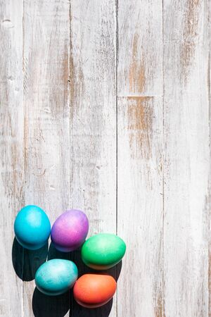A rainbow of Easter Eggs on a white and weathered wood background.の写真素材