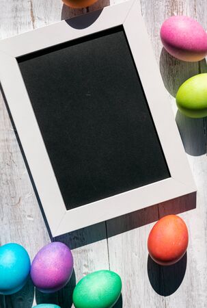 A rainbow of Easter Eggs on a white and weathered wood background.の写真素材