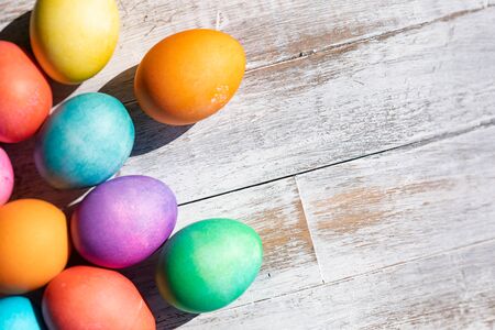 A rainbow of Easter Eggs on a white and weathered wood background.の写真素材