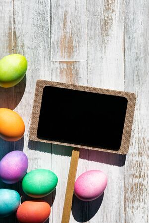 A rainbow of Easter Eggs on a white and weathered wood background.の写真素材