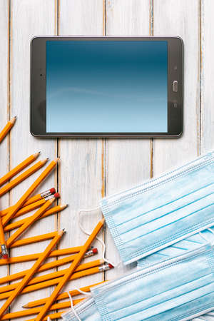 Series on weathered wood background with school items, as well as face masks and hand sanitizer for back to school.の写真素材