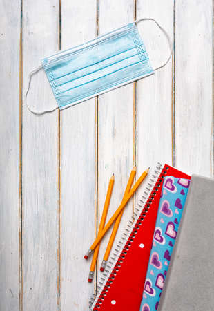 Series on weathered wood background with school items, as well as face masks and hand sanitizer for back to school.の写真素材