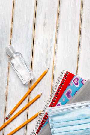 Series on weathered wood background with school items, as well as face masks and hand sanitizer for back to school.の写真素材