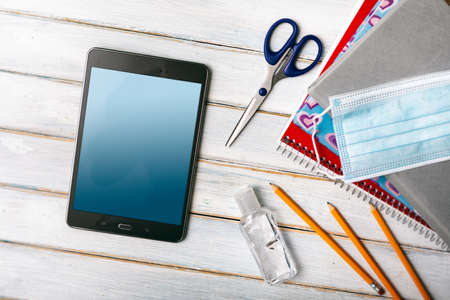Series on weathered wood background with school items, as well as face masks and hand sanitizer for back to school.の写真素材