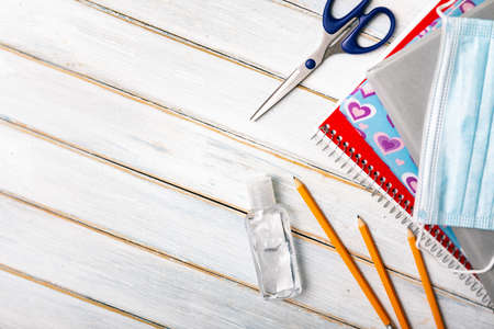 Series on weathered wood background with school items, as well as face masks and hand sanitizer for back to school.の写真素材