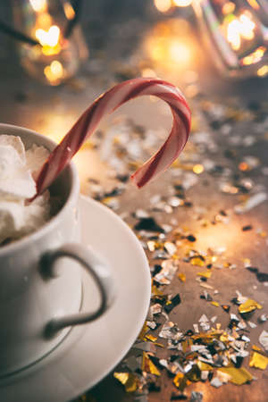 Holiday: Candy Cane In Mug Of Cocoa With Light Bulbs Behindの写真素材