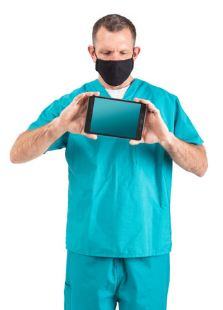 Male physician in scrubs and a mask, during the covid-19 pandemic.の写真素材
