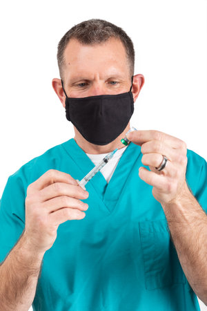 Male physician in scrubs and a mask, during the covid-19 pandemic.の写真素材