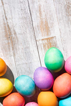 A rainbow of Easter Eggs on a white and weathered wood background.の写真素材