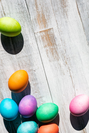 A rainbow of Easter Eggs on a white and weathered wood background.の写真素材