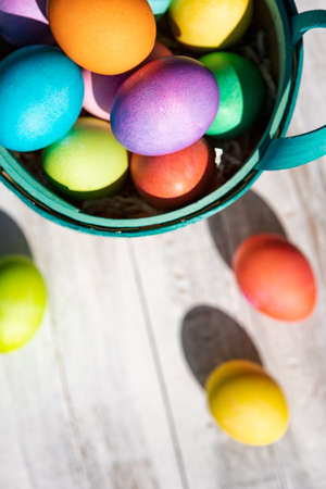 A rainbow of Easter Eggs on a white and weathered wood background.の写真素材