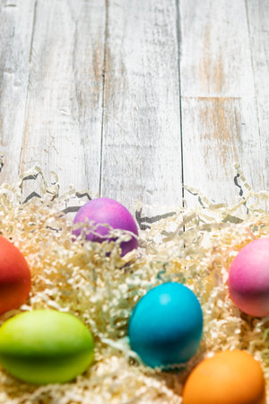 A rainbow of Easter Eggs on a white and weathered wood background.の写真素材