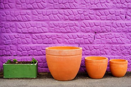 Colourful pots on gravelroad next to purple wallの写真素材