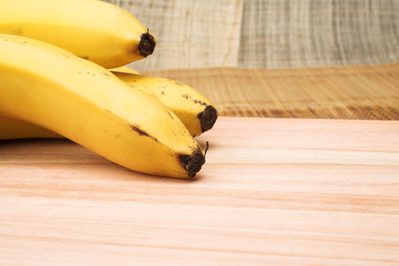 Three bananas on a wooden cutting board - copy spaceの写真素材