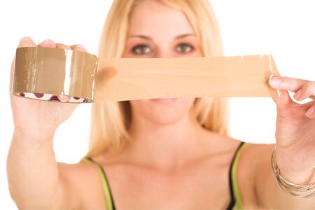 Blonde business lady in an informal green top. Holding a piece of tape.  Shallow DOF - hands and tape in focus, face out of focus.の写真素材