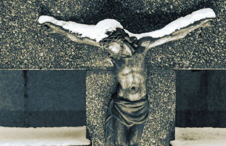 Gravestone  with statue of Christ covered in snow.  Sepia and blue tone.の写真素材