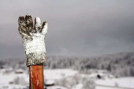 Glove on wooden pole with snow in the background.  Copy spaceの写真素材