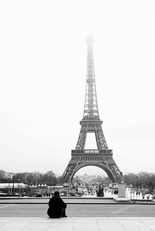 A person sitting, looking at the Eiffel Tower in Paris, France.  Black and white.  Copy space.の写真素材