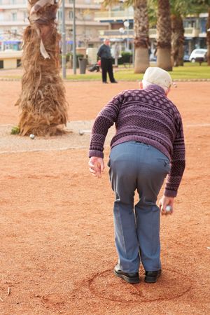 An old man playing petanque in Antibes, France.  Movement on person's right hand.  Copy space.の写真素材