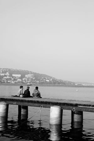 Three kids fishing from the pier on Ile Sante-Marguerite  Cannes in Background, Franceの写真素材