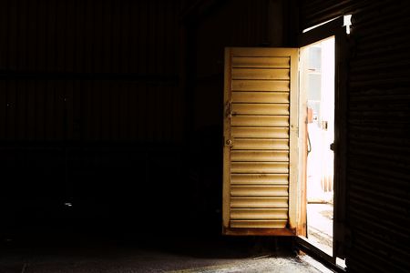 Open door to an industrial warehouse - shaft of light, High contrastの写真素材