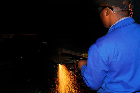 Worker in blue safety wear, working with Plasma cutter - Focus on person, not on sparks