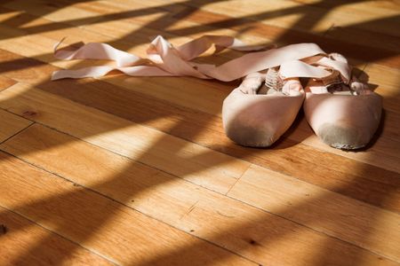 Pair of Ballet shoes lying on a wooden studio floorの写真素材