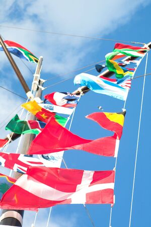 Various flags of various countries displayed together on a signal mast of a ship (focus on the red flags at the bottom)の写真素材