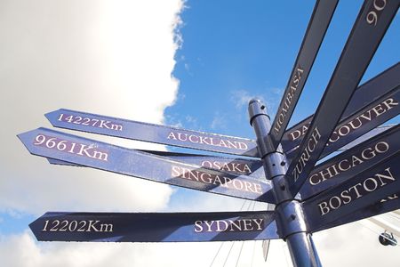 A blue distance marker against a cloudy blue sky for the various cities in the world (in km)の写真素材