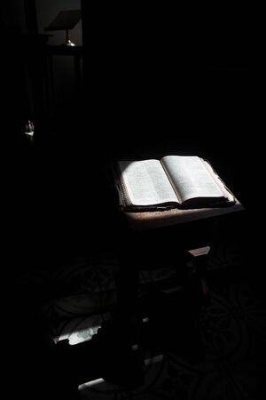 Old open bible lying on a wooden table in a beam of sunlight (not an isolated image) Shallow Depth of field  Focus on middle textの写真素材