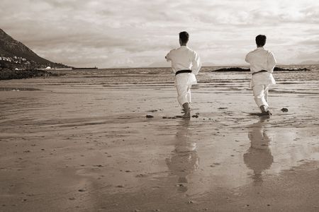 Young adult men with black belt practicing a Kata on the beach on a sunny dayの写真素材