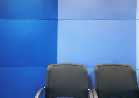 Two grey office chairs against blue soundproof blue panels in a modern boardroomの写真素材