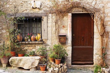 Street garden with Street name and potted plants in front of windows and doors in the quaint little French hilltop village of Saint-Paul de Vence, Southern France,  Alpes Maritimes, next to the Mediterranean sea - a Heritage Siteの写真素材