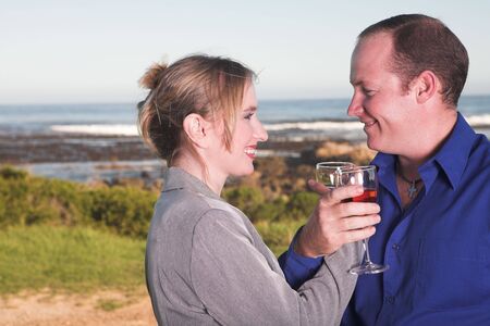 Young adult Caucasian couple drinking wine outdoor next to the oceanの写真素材