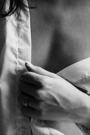 Young adult Caucasian woman in a white shirt and lingerie, undressing as a part of foreplayの写真素材