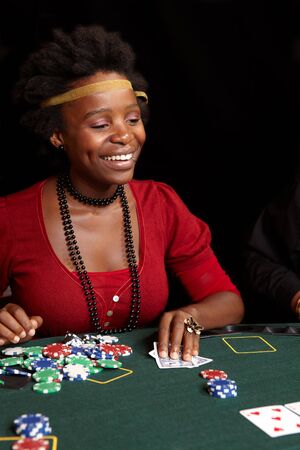 African Woman playing cards, chips and players gambling around a green felt poker table. Shallow Depth of fieldのeditorial素材