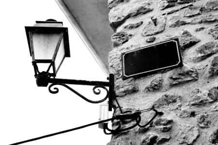 Streetlight and a blank sign against a stone wall in Antibes, France. Black and white. Copy spaceの写真素材