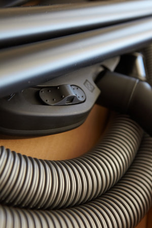 Spare parts and pipes of a new vacuum cleaner in a brown cardboard box, being unpacked