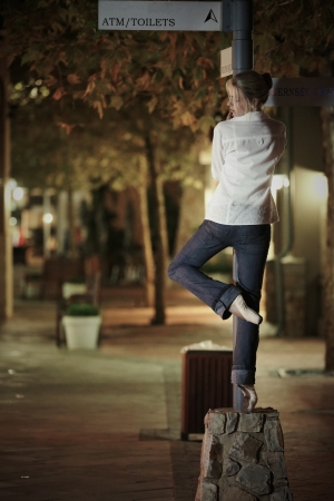 Young adult blonde ballerina dancing at night under signs and lamp posts in a general urban area  Shallow Depth of Fieldの写真素材