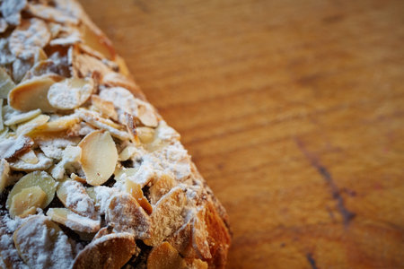 Fresh chocolate and Almond rollover croissant pastry, sprinkled with icing sugar on a brown wooden...