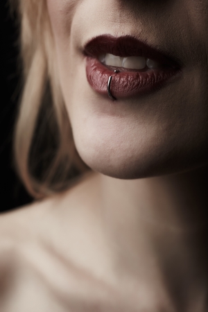 Close up portrait of the pierced red lips of a beautiful young adult caucasian woman in a black gownの写真素材
