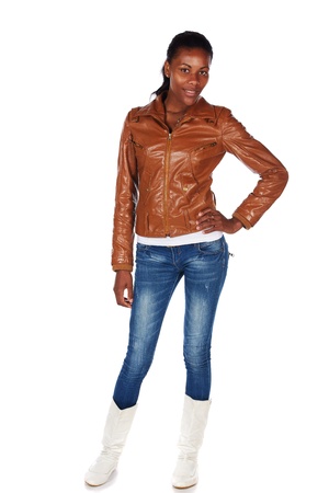 Beautiful black african young adult woman casually dressed in a brown leather jacket and Blue jeans with white bootsの写真素材