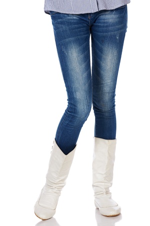 Legs and boots of a stylish and thin black african young adult woman casually dressed in blue jeans and white boots and isolated on a white backgroundの写真素材
